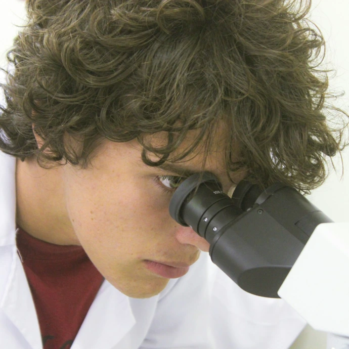 A young scientist examines through a microscope.